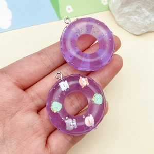 Dettaglio di ciondoli a forma di ciambella in resina viola con glitter e cartoni