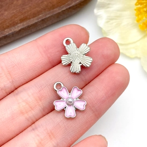 Dettaglio di fiori in smalto rosa e ciondoli in metallo argentato per gioielli DIY