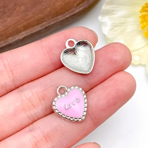 Dettaglio ciondolo a cuore rosa smaltato con scritta Love per creazione gioielli