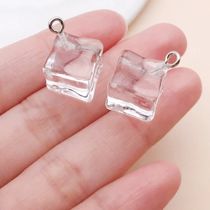 Close-up of a clear resin ice cube charm with a silver metal hook for DIY jewelry
