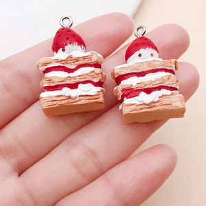 Close-up of DIY resin strawberry cake charms held by hand with detailed cream layers