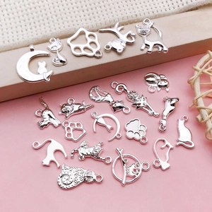 Detailansicht polierter silberner Katzen-Anhänger und Pfotenabdrücke für DIY-Schmuck
