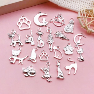 Detailansicht von 20 silbernen Katzenanhängern auf rosa Grund für DIY-Schmuckherstellung