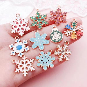 Hand mit bunten Weihnachts-Schneeflocken-Anhängern aus Legierung für DIY-Schmuckbau