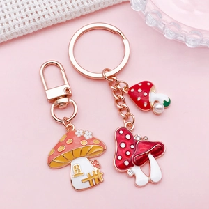 Enameled mushroom house keychains with rhinestones and imitation pearls on pink background