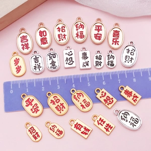 Macro detail of DIY jewelry charms with Chinese blessing symbols on a soft pink background