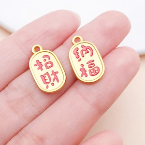 Close-up of gold-plated oval pendants with red enamel Zhaocai and Nafu characters