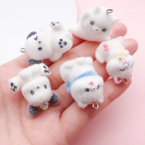 Cute white flocked puppy charms for DIY accessories shown in hand for scale
