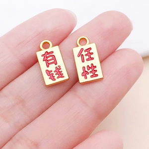Macro detail of gold charms with red calligraphy characters for jewelry making