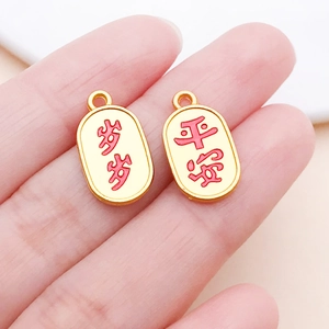 Macro detail of gold-plated oval pendants featuring engraved red Chinese characters for blessing