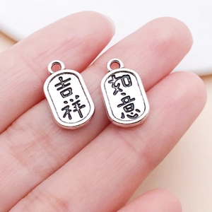 Macro detail of silver oval charms with Lucky Chinese characters for DIY jewelry making