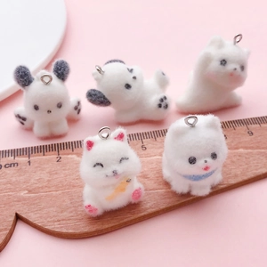 Close-up of cute flocked resin puppy pendants with metal rings and ruler for size reference