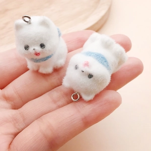 Detail showing two miniature white flocked dog charms held in hand for size context