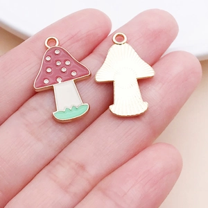 Detailed close-up of mushroom charms showing colorful enamel front and gold textured back