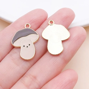 Detailed view of enamel mushroom charm pendant with gold metal back and top ring