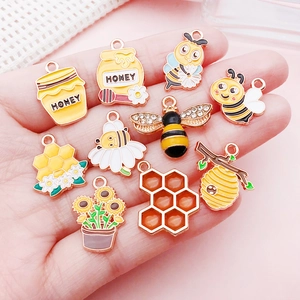 Detailed view of ten cute yellow enamel bee and sunflower charms on a palm background