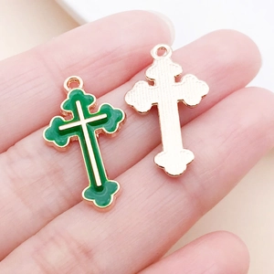 Gros plan de pendentifs croix en émail vert avec bords dorés et base en métal mat