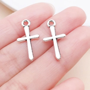 Gros plan de pendentifs croix en alliage argenté pour bijoux DIY sur le bout du doigt