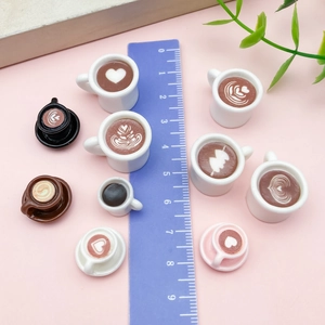 Draufsicht auf Miniatur-Kaffeetassen mit Herz-Latte-Art und einem Messlineal daneben