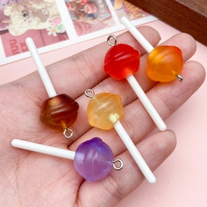 Hand holding colorful glitter resin lollipop charms with silver rings for DIY jewelry