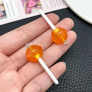 Detail of orange resin lollipop charms with glitter and metal loops for DIY jewelry