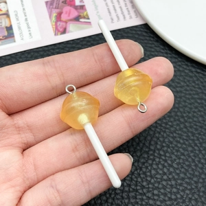 Close-up of yellow resin lollipop pendants for DIY crafts held in hand for scale