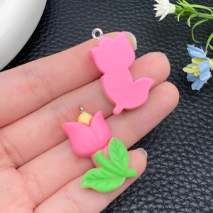 Detail van roze hars tulp en kat bedeltjes voor het maken van DIY-sieraden