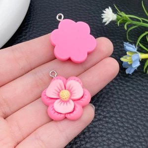 Detail van twee roze bloemhangers van hars met gele meeldraden en zilveren metalen ringen