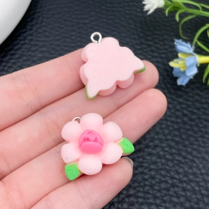 Detail van roze hars roos bloem hanger met groene bladeren en een zilveren metalen ring