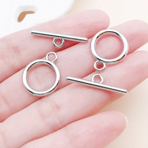 Gros plan de fermoirs à bascule OT en métal argenté pour bijoux avec référence de taille à la main