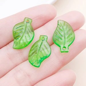 Vue macro de trois breloques feuilles en acrylique vert translucide pour bijoux DIY