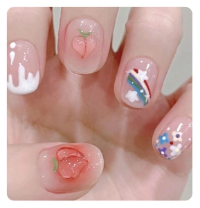 Detailed view of handmade press-on nails featuring peach charms and rainbow art