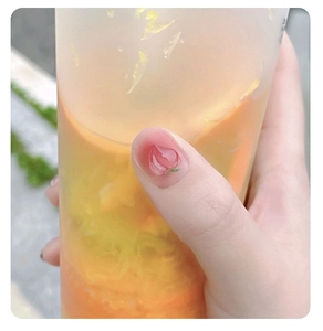 Close-up of 3D pink peach nail charm on thumb with natural summer lighting background