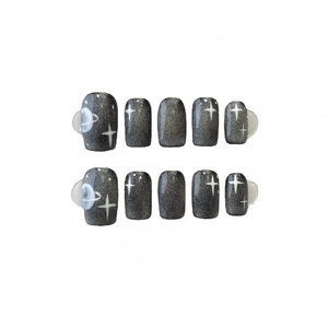 Cat eye press-on nails with dark galaxy design featuring white star and planet patterns