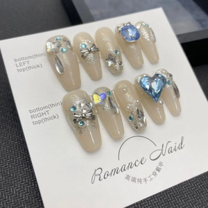 Handmade press-on nails with blue heart gems, silver bows and sparkling glitter gradients