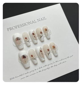 Macro detail of handmade press-on nails with red rose patterns and silver 3D borders