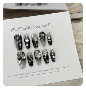 Detailed view of handmade press-on nails with black gradient, rhinestones, and snowflakes