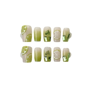 Handmade press-on nails with lemon art and 3D green heart rhinestones on white background