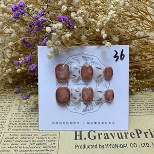 Macro shot of 10pcs nude coffee ombré press-on nails with hand-painted camellia flower art