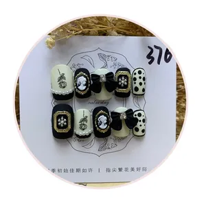 Macro view of handmade press-on nails featuring vintage cameos and 3D black bows