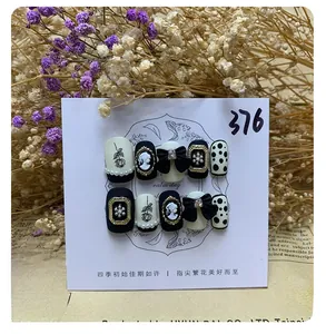 Macro shot of black handmade press-on nails with 3D relief portraits and pearl details