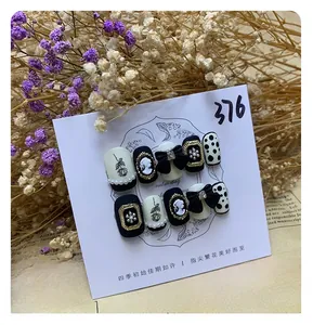 Detail of handmade black press-on nails with 3D cameo, bows and pearl accents