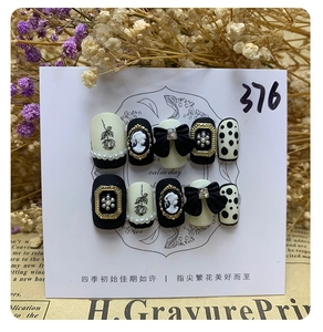 Detail of press-on nails with 3D black bows, vintage cameo, and rose motifs