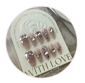 Detail of luxury press-on nails with pink heart rhinestones and pearls on display card