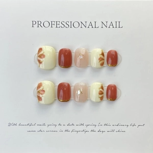 Detail of handmade press-on nails featuring red floral art and gold foil accents