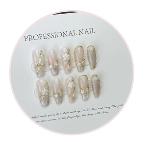 Detail of handmade press-on nails with 3D white flowers, pearls and golden outlines