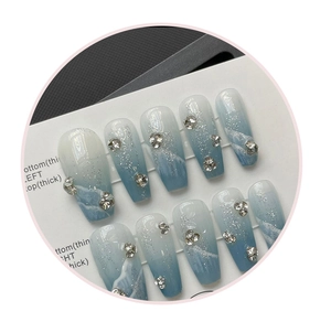 Detail of handmade ice blue gradient press-on nails with silver glitter and rhinestones