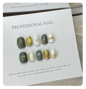 Macro shot of 3D embossed floral nail art with vintage green and pearl accents