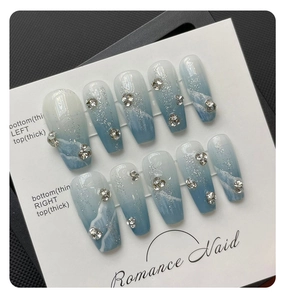 Macro detail of blue marble gradient press-on nails with silver glitter and rhinestones