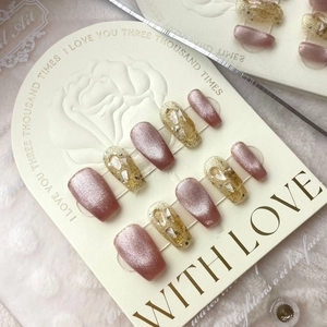 Detailed close-up of handmade press-on nails with rose pink cat-eye and gold glitter finish